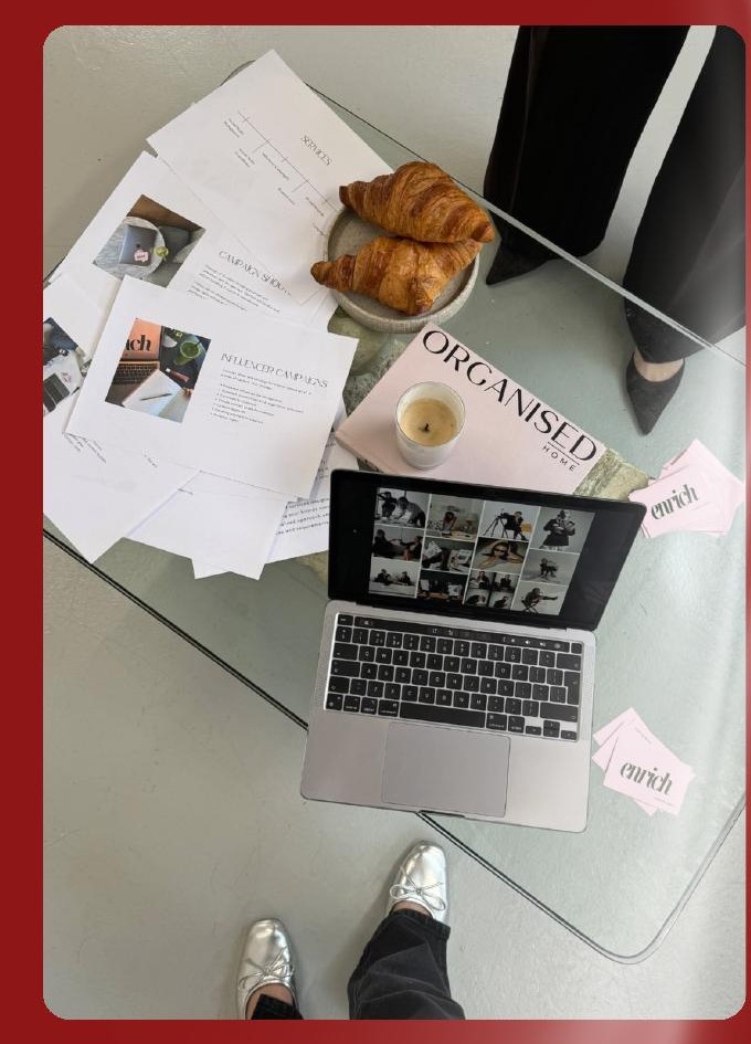 Workspace desk with campaign moodboards, a laptop, and croissants